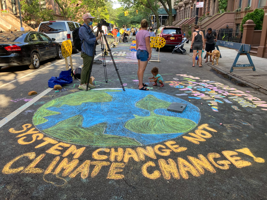 Chalk art on the road of the earth alongside the words 'System change not climate change'